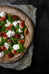 Neapolitan pizza with figs, ham and burrata cheese. Dark background
