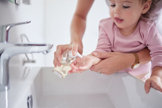 Mother Cleaning Kids Hands With Sanitizer Liquid Soap After Baby Toddler Had Dirty Fingers In The Sink. Healthy, Grooming And Mom Cleaning And Helping A Young Girl With Hygiene Wellness At Home