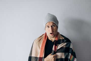 Guy is wrapped in blanket and warms his hands from the cold. Heating season. Winter has come,...