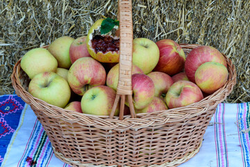Basket full of apples, on top is an apple with jam, in the background straw in the countryside