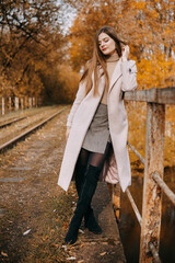 beautiful long-haired woman walks through the autumn streets. Railway, autumn, woman in a coat.