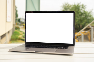 Fototapeta premium Laptop with white screen in business office or shopping mall. Empty copy space, blank screen mockup. Soft focus laptop with interor background. Travel, study and office work concept