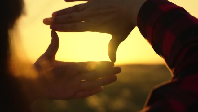 Concept of seeing world as different, Sees like in movies. Hands of young female director cameraman making frame gesture at sunset. Business planning. Girl shows her fingers frame symbol in sun
