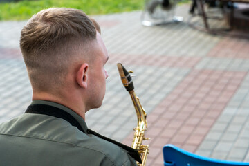 A young handsome guy with a saxophone in his hands. A military band, a musician in a military...