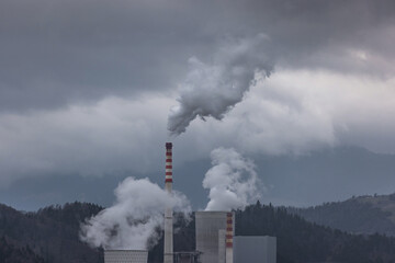 The heavy gray sky over thermal power plant smokestacks that blow out smoke and smog, burning coal...