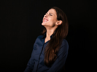Beautiful funny toothy laughing business woman with folded arms in blue shirt on black background with empty copy space for text. Closeup