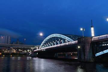 ライトアップされた隅田川駒形橋と月と都市夜景