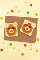 Funny cute bear faces sandwich toast bread with peanut butter, banana,nuts. Kids childrens baby's sweet dessert healthy breakfast lunch food art on plate,close up,top view