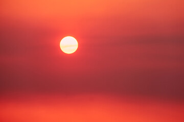 Obraz premium A big red sun in the sunset sky, a summer landscape. Evening sky in hot sunlight