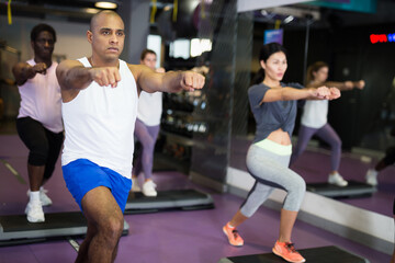 Fototapeta na wymiar Man with others doing step aerobics in a fitness club