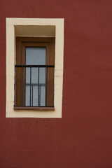 Colorful red colored facade with window details on a Latin Colonial building.