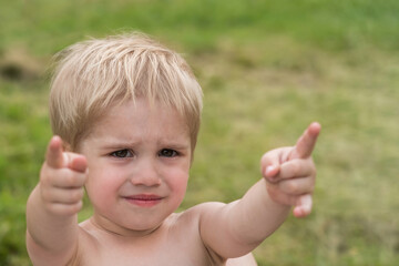 Nice offended kid with insulted expression face, points with forefingers (concept of children's emotions)