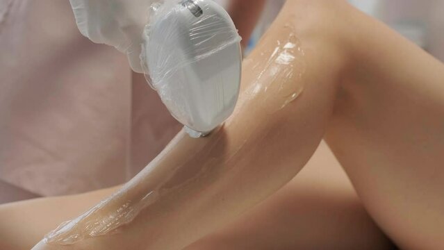 Laser epilation - hair removal procedure. Flash of diode laser hair removal, Beautician removes hair on beautiful female legs, Hair removal for smooth skin, laser procedure at beauty studio or clinic,