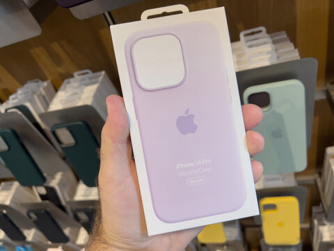 Paris, France - Sep 16, 2022: POV male hand holding package in Apple Store shopping with new purple iPhone 14 Pro leather case with MagSafe charging