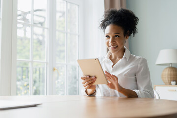 A woman at home uses a tablet running online training in the app.