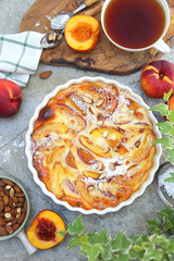 Nectarine clafoutis (flan) with almonds, icing sugar dressing and cup of tea - 531541852