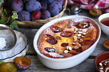 Damson blue plum clafoutis (flan) and cup of tea, icing sugar and almonds dressing