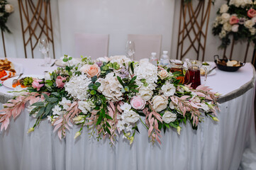 Beautiful multi-colored flowers hang on a table with a white sheet and food. Wedding decorations, close-up photography.