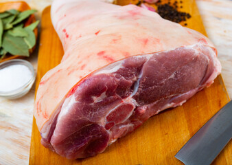 View of a fresh pork ham lying on a cutting board on the table. High quality image