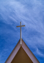 Tan Arched  Steeple with a White Cross Under Blue Sky with Cirrus Clouds.