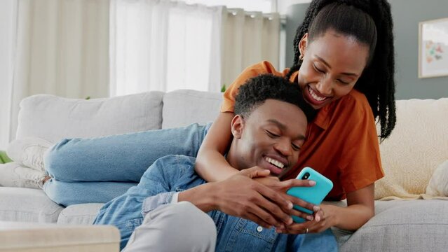 Phone, meme and happy couple on social media laughing at comic, comedy and funny content together at home. People, love and black woman with black man sharing online entertainment on sofa to relax