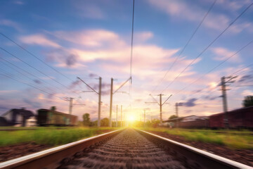 Railway tracks in motion at sunset. Railroad with motion blur. effect. Rail tourism, rail transportation.