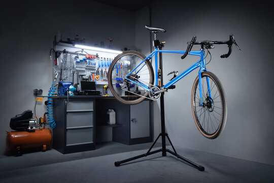 Bicycle workshop for repairing bicycles. Bicycle hanging on a repair stand in the background of a workbench with professional tools. Bicycle service.