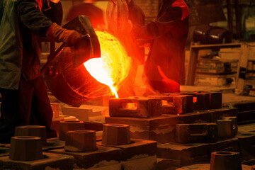 The liquid metal or cast iron poured into molds. Metal casting process with red high temperature...