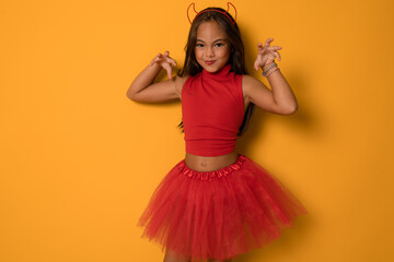 Portrait of an angry little girl in a costume, on a orange background. halloween.