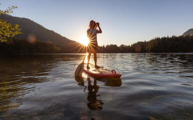 Adventurous Woman Paddling on a Paddle Board in a peaceful lake.