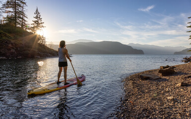 Adventurous Woman Paddling on a Paddle Board in a peaceful lake. - Powered by Adobe