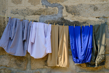 Colorful clothes drying in the sun. Shirts and trousers are hung on the clothesline. 