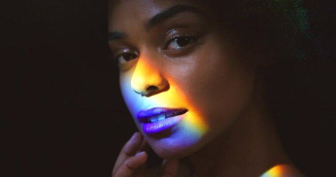 Rainbow face, woman and portrait of beauty makeup with optical flare in studio for pride campaign. Sensuality, equality and lgbt black person with a fantasy colorful light effect on skin.