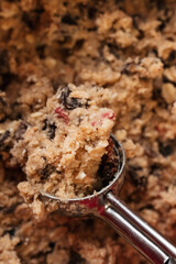 Close up of raw oatmeal raisin cookie dough made of flour, rolled oats, sugar, eggs, raisins and dried fruit in stainless steel cookie scoop - 531552629