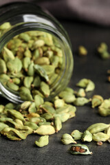 Jar with dry cardamom pods on dark grey table