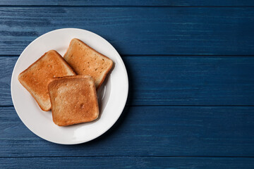 Plate with slices of delicious toasted bread on blue wooden table, top view. Space for text