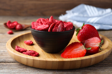 Freeze dried and fresh strawberries on wooden table, closeup