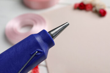 Hot glue gun on blurred background, closeup