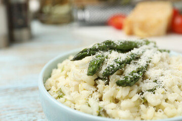 Delicious risotto with asparagus and cheese in bowl, closeup
