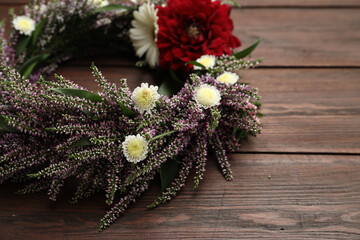 Beautiful autumnal wreath with heather flowers on wooden background, closeup