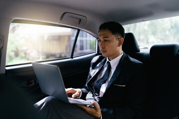 Asian businessman working on his laptop in the car.