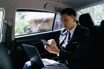 Happy smiling business man typing message on phone while sitting in a car.