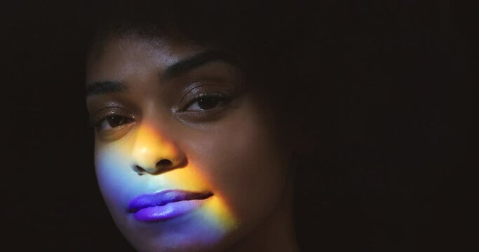 Rainbow, prism light and face of a black woman with creative lighting reflection. Portrait of a young model from Jamaica relax with colorful art projection on skin represent pride and freedom
