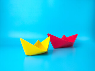 Leadership concept. Red leader paper ship leading among others on blue background...