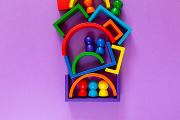 Multicolored abstract rainbow background. Wooden kids toys on violet paper. Educational toys blocks, rainbow. Toys for kindergarten, preschool or daycare. Copy space for text. Top view 