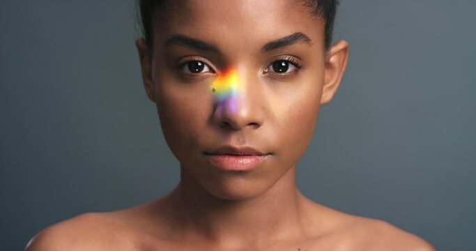 Art, creative and rainbow light with black woman standing in power against studio background. Portrait of African American female face show support and pride of gay, lgbt and alternative lifestyle