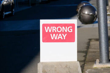 A red and white road sign with wrong way in the middle of road