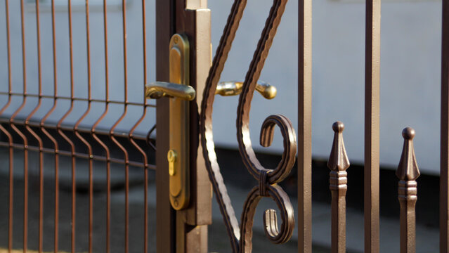 Defocus forged decor of forged elements for metal gates. Forged metal fence in retro style. Gate with forged elements of gold color. Out of focus