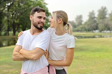 young couple caucasian people are in love. man and girl wearing white shirt hugging in the park during summer season with smiling and happy face