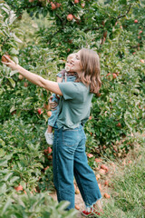 A mom and her toddler pick apples from a tree at an apple orchard